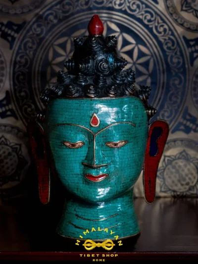 Volto di Buddha Shakyamuni in ottone decorato con mosaico di corallo rosso e turchese, simbolo di saggezza e illuminazione spirituale, con riferimento al mantra Om Muni Muni Maha Muni Shakyamuni Ye Soha