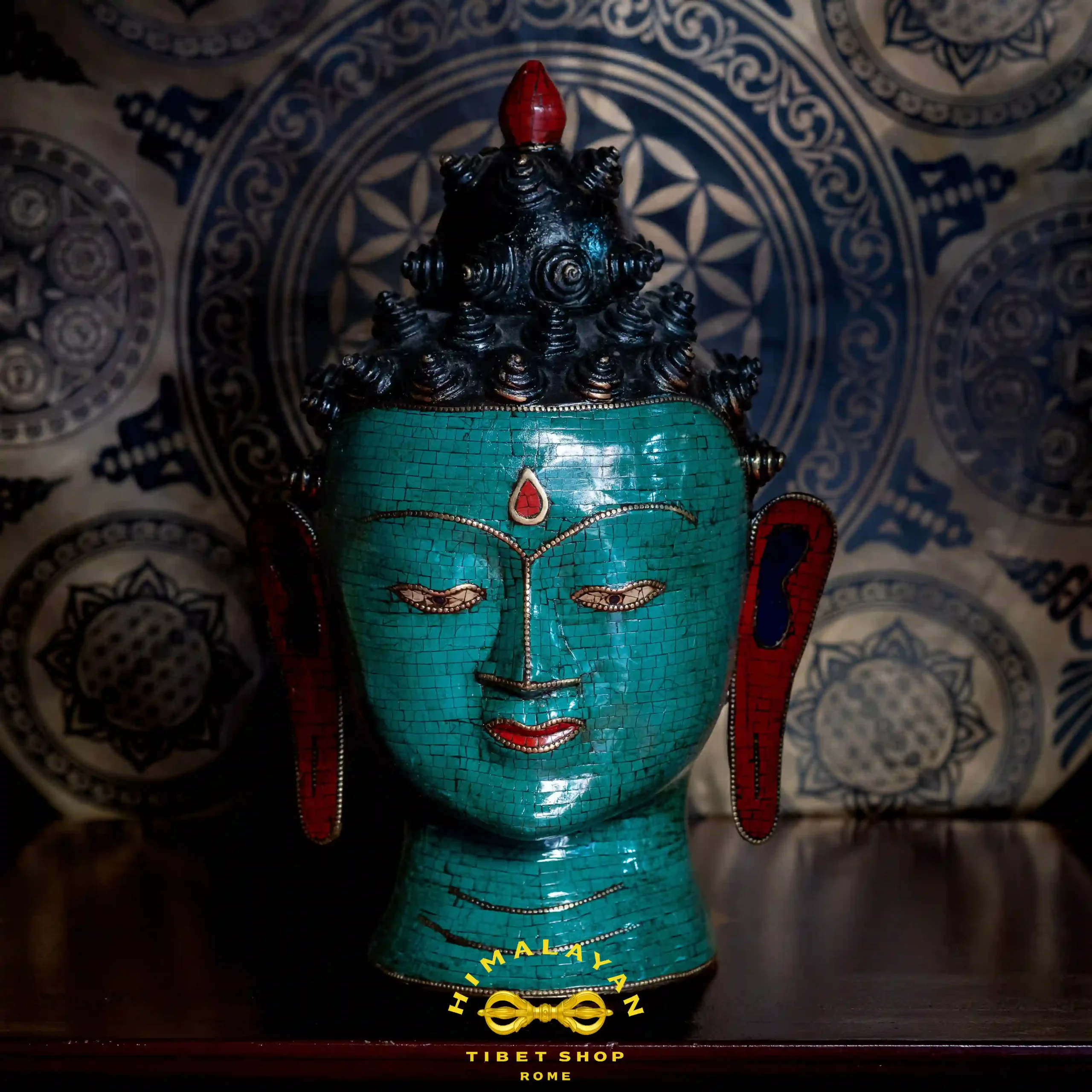 Volto di Buddha Shakyamuni in ottone decorato con mosaico di corallo rosso e turchese, simbolo di saggezza e illuminazione spirituale, con riferimento al mantra Om Muni Muni Maha Muni Shakyamuni Ye Soha